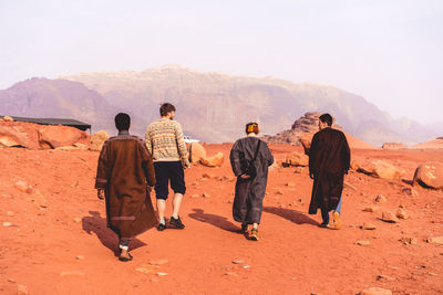 Rear view of people walking on mountain against sky