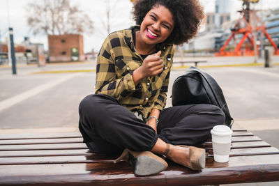 Full length of smiling man sitting on woman in city