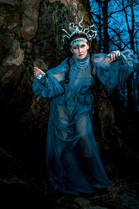 A gloomy full length portrait of a woman in makeup and a night witch costume on a dark background