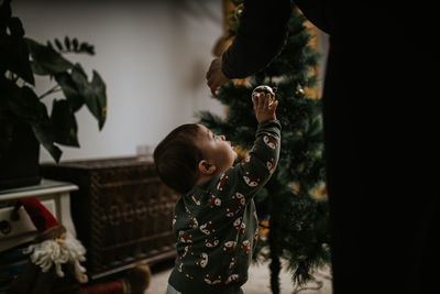 Rear view of boy holding christmas decorations