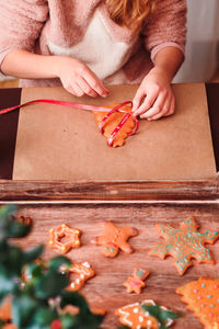 Midsection of woman preparing gingerbread cookies on cutting board
