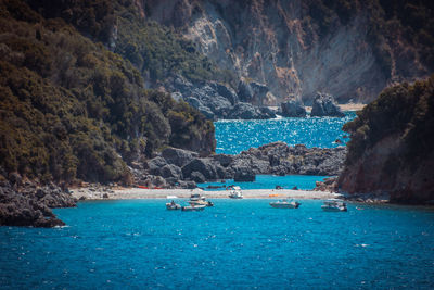 Scenic view of sea by mountain against sky