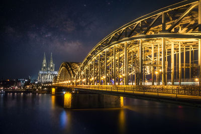 Illuminated bridge over river at night