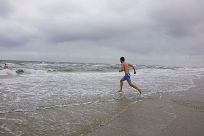 Full length of friends on beach against sky