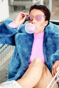 Woman blowing bubble gum while sitting in shopping cart