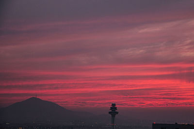 Silhouette of tower against cloudy sky during sunset