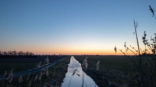 Scenic view of land against clear sky during sunset