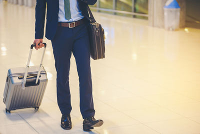 Low section of businessman with luggage walking at airport