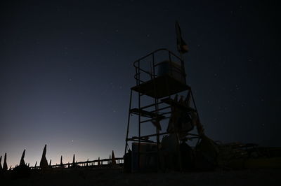 Low angle view of silhouette tower on field against sky at night