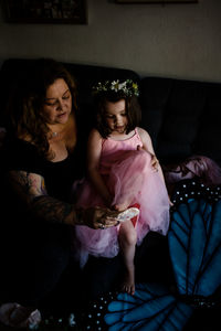 Aunt helping niece put on ballet shoes