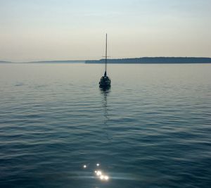 Sailboat in sea against sky during sunset