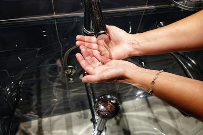 Cropped hands of woman washing hands in sink