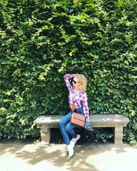 Full length of woman sitting on bench in park