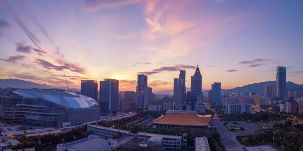 Modern buildings in city against sky during sunset