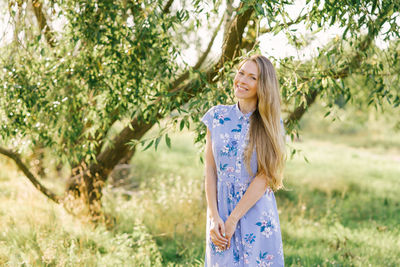 Cute young woman in a blue dress smiles while walking in the park person