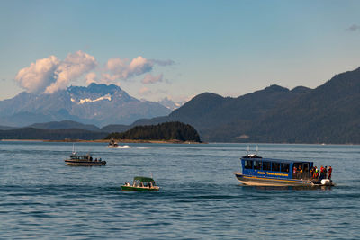 Boats sailing in sea against mountains