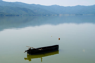 Boat floating on lake against mountains