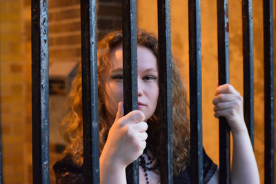 Portrait of woman standing by fence