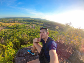 Young man using mobile phone while sitting on mountain