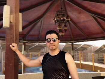 Portrait of young man standing against ceiling