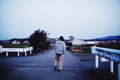 Rear view of man walking on mountain against clear sky