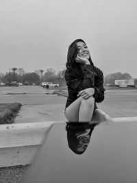 Young woman standing on road against sky