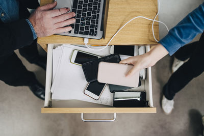 High angle view of female student collecting phone in drawer during exam in school