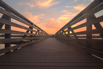 Wooden bridge against cloudy sky