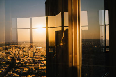 Buildings against sky during sunset seen through glass window