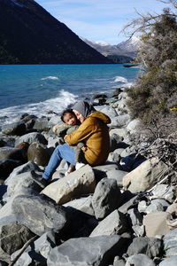 Rear view of man sitting on rock