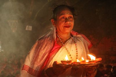 Women holding dia-oil lamp on hand in a smokey environment