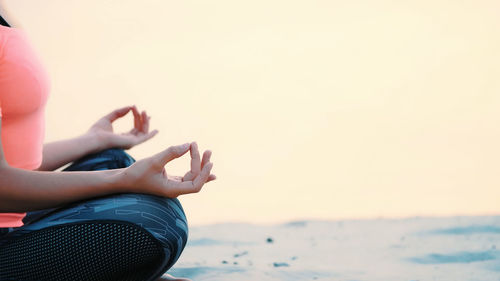Healthy, young beautiful woman meditating, practicing yoga on the beach, by the sea, at sunrise