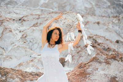 Portrait of young woman standing against rock