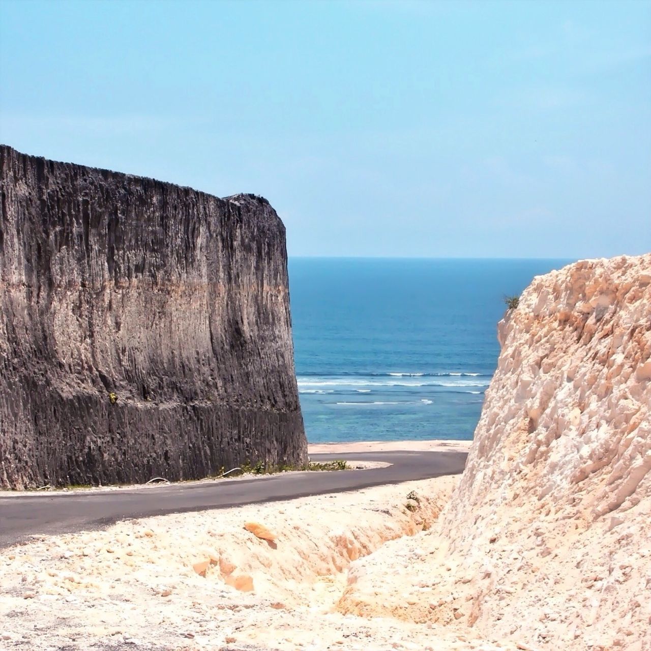 sea, horizon over water, tranquil scene, clear sky, tranquility, beach, water, rock formation, scenics, beauty in nature, blue, nature, cliff, sand, shore, rock - object, copy space, rock, idyllic, coastline