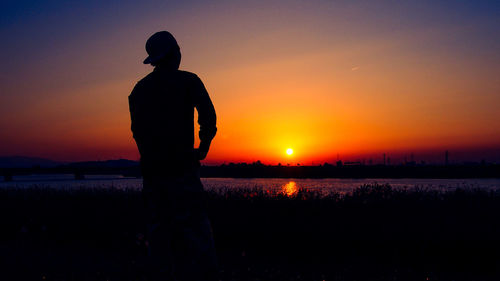 Silhouette man against orange sky during sunset