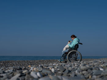 Rear view of man riding bicycle on beach against clear sky