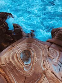 Waves crashing against the rocks at the boot on of a cliff, vibrant colours 