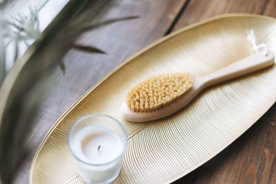 Details of interior, aromatic candle in glass and wooden brush with natural bristles on metal tray 