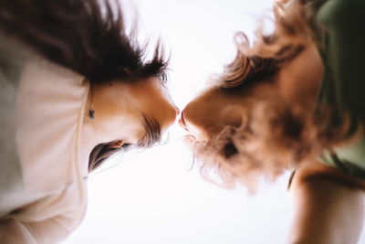 Low angle view of lesbian couple standing face to face about to kiss