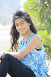 Portrait of smiling young woman sitting outdoors