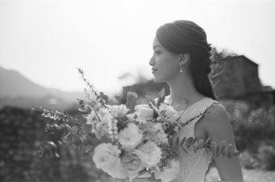 Close-up of woman with flowers on field against sky