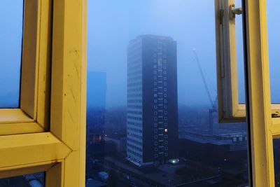 Modern buildings in city against sky seen through window