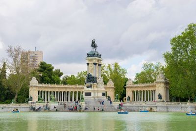 Statue in front of historical building against cloudy sky