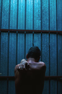 Close-up of shirtless man standing against wall