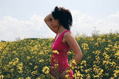 Woman standing in field of yellow flowers