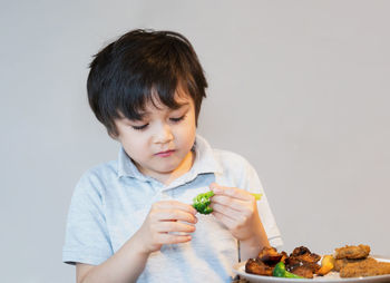 Portrait of boy holding food against white background