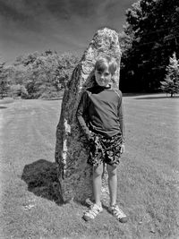 Portrait of boy standing against rock on field