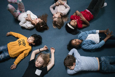 Directly above shot of school children lying on floor in classroom