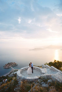 Rear view of woman standing by sea against sky