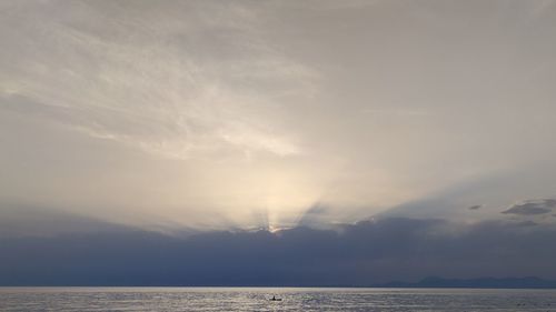 Sunlight streaming through clouds over sea